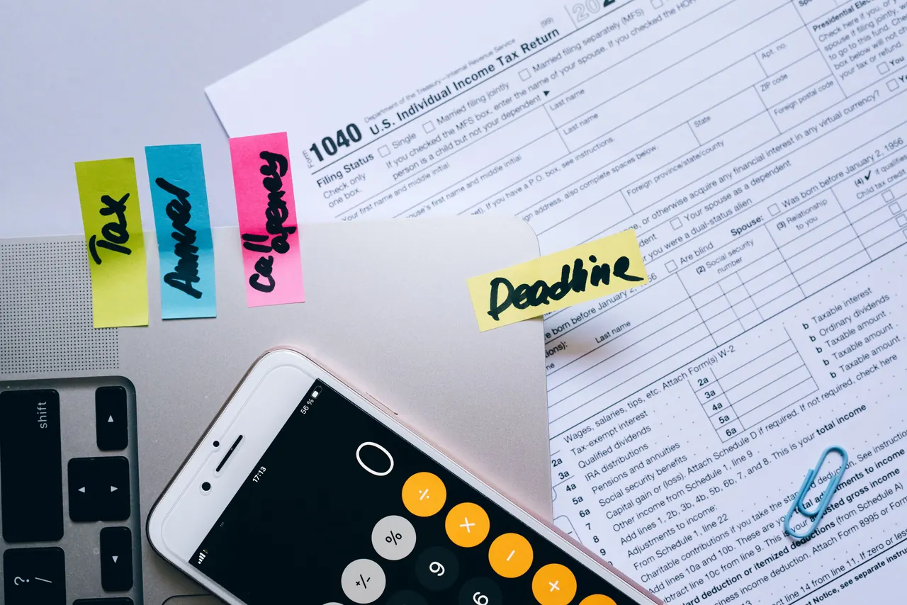 Tax documents, sticky notes, a phone and a calculator laid out on a desk