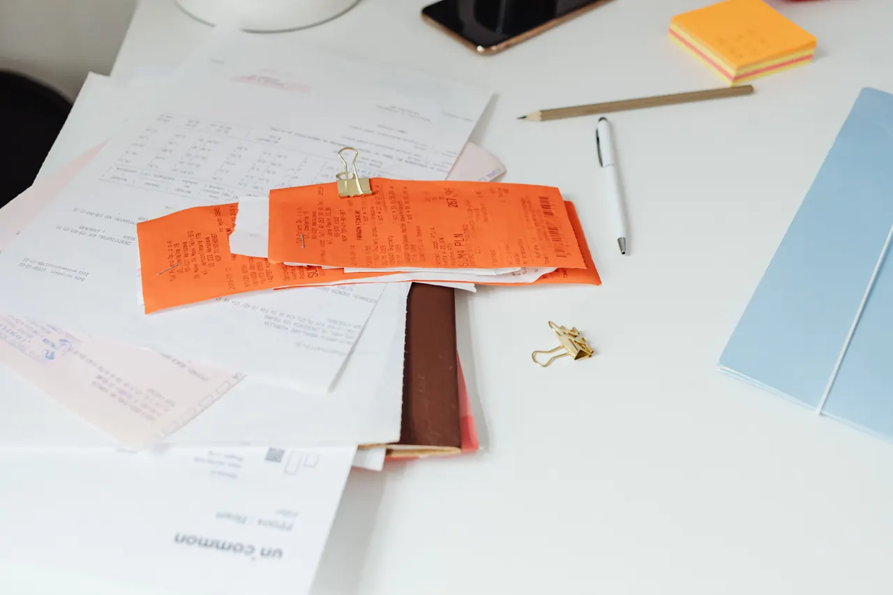 A tidy desk with a pile of paper receipts and documents